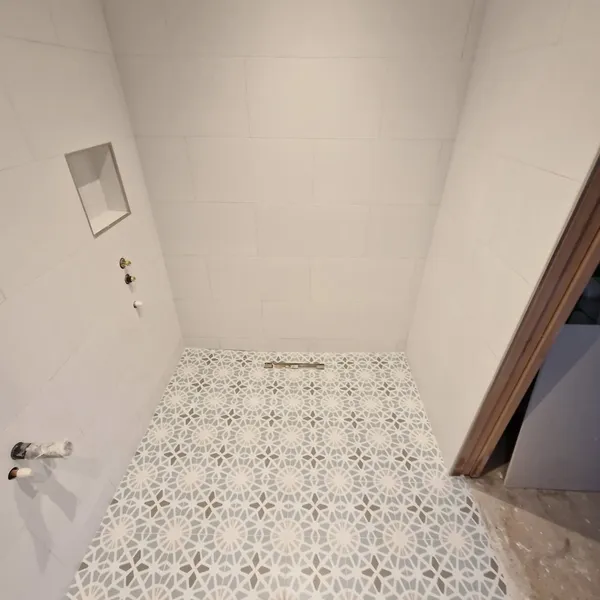 Walk-in shower with geometric patterned floor tiles and recessed niche