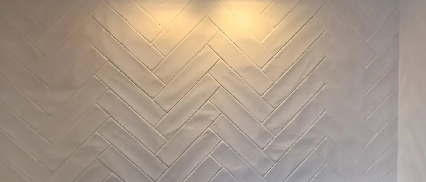 White herringbone tile backsplash installed behind a kitchen cooktop