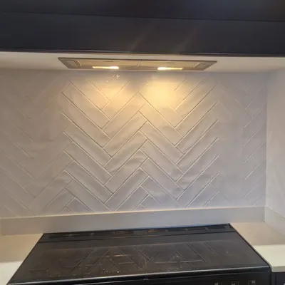 White herringbone tile backsplash behind kitchen hob