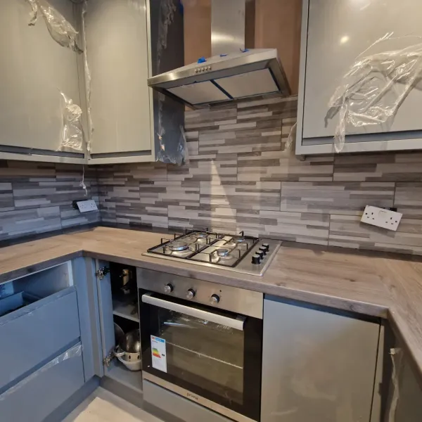 Grey split-face effect tile backsplash in a kitchen with wood worktop
